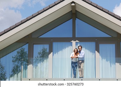 young couple standing on balcony of their house