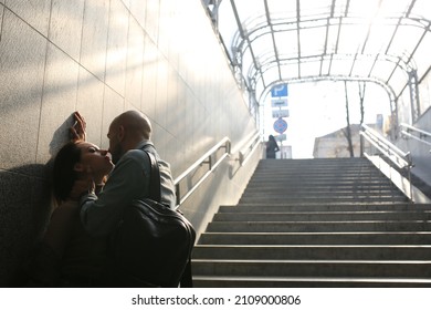 A young couple is standing on the stairs of the underpass near the wall. Kiss moment. Place for your text. High quality photo