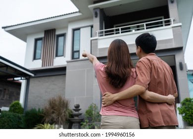 young couple standing outside and looking their house
