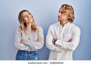 Young Couple Standing Over Blue Background Looking To The Side With Arms Crossed Convinced And Confident 