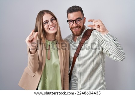 Young couple standing over white background smiling and confident gesturing with hand doing small size sign with fingers looking and the camera. measure concept.  Stock photo © 