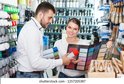 Young couple standing with tools using palette scheme in paint shop