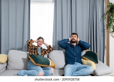 Young couple stares at the ceiling and yells because a neighbor upstairs is having a party with loud music or renovating an apartment and workers are drilling with heavy tools. Nise pollution concept - Shutterstock ID 2095928758