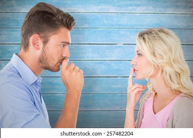 Young Couple Staying Silent With Fingers On Lips Against Wooden Planks