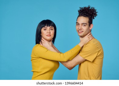   young couple strangling each other look into the camera on a blue background                             