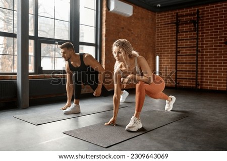 Young couple stretching legs at training gym class