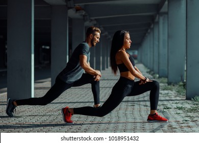 Young couple stretching legs in urban environment