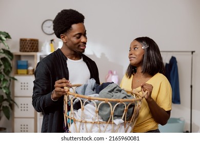 A young couple of students live together in an apartment. The woman is doing household chores, sorting laundry in a wicker basket, the man is helping the girl to put in the washing machine. - Powered by Shutterstock