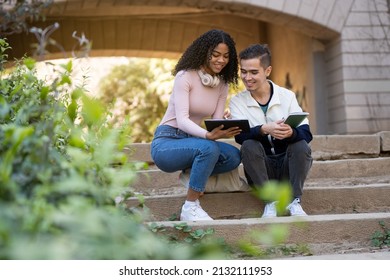 Young couple of students sitting on some stairs looking at a digital tablet - Powered by Shutterstock