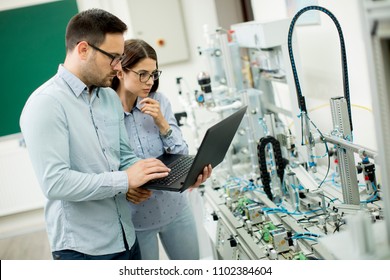 Young couple of students working with laptop at robotics lab - Shutterstock ID 1102384604
