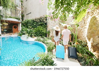 Young couple with suitcases walking to room of luxurious spa resort, view from the back - Shutterstock ID 1946727550