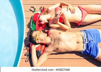 Young couple sun tanning at pool deck of cruise ship - Beautiful lovers holding hands lying on yacht poolside - Concept of unforgettable love moment on the honeymoon vacation - Soft vintage filter - Powered by Shutterstock