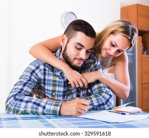 Young Couple At The Table Filling Together Forms For Joint Banking Account
