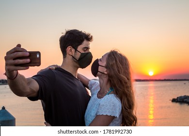 A Young Couple Take A Selfie At Sunset Wearing Face Mask -  Concept About New Normal During Coronavirus