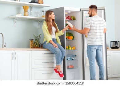 Young Couple Taking Food Out Of Fridge In Kitchen