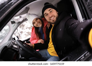 Young couple taking selfie in car. Winter vacation - Powered by Shutterstock