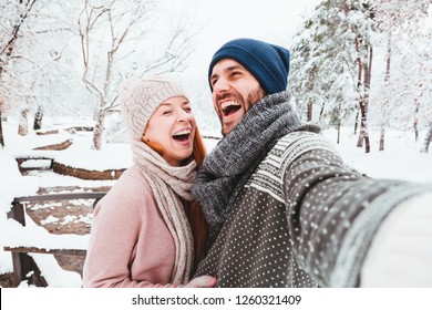 Young couple taking a selfie in a park on a snowy day - Powered by Shutterstock