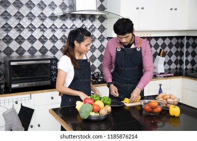 young couple is talking and smiling while cooking healthy food in kitchen at home.
