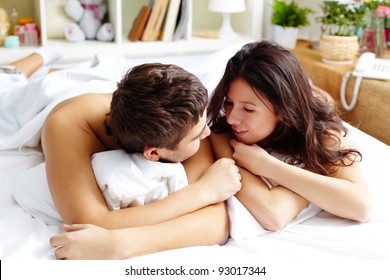 Young couple talking while lying in bed in the morning