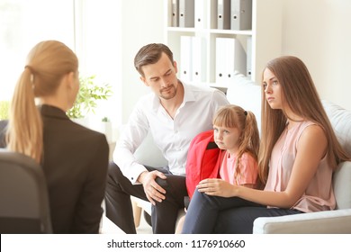 Young couple and their daughter meeting with headmistress at school