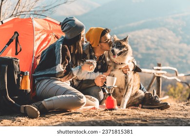 Young couple and their dog camping in the mountains on a beautiful autumn day spending time outdoors and appreciating nature. - Powered by Shutterstock