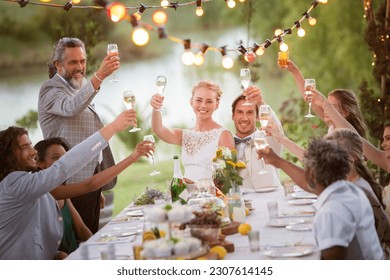 Young couple their guests toasting champagne during wedding reception in garden - Powered by Shutterstock