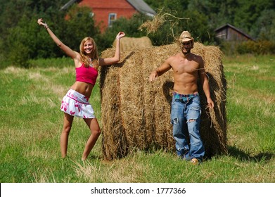 Young Couple Throwing Hay In The Air In A Hay Field.