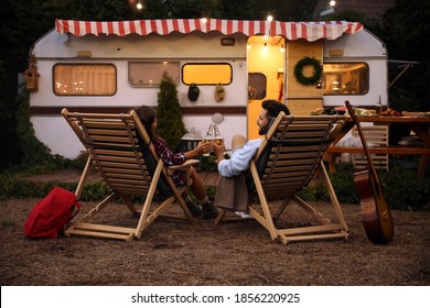 Young couple toasting with bottles of beer near trailer. Camping season - Powered by Shutterstock