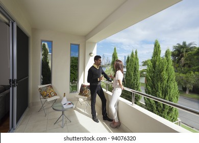 Young couple toasting with champagne on a modern backyard overlooking the city - Powered by Shutterstock