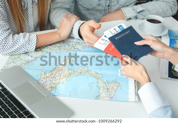 Young couple in\
a tour agency communication with a travel agent travelling concept\
passports and tickets