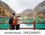 Young couple tourist taking a photo of the beautiful autumn scenery landscape at the Jiuzhaigou national park in sichuan, China