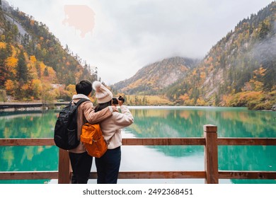 Young couple tourist taking a photo of the beautiful autumn scenery landscape at the Jiuzhaigou national park in sichuan, China - Powered by Shutterstock