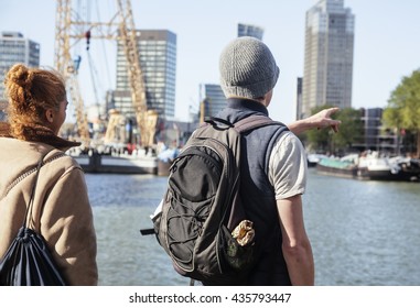 Young Couple Tourists Looking And Pointing To Rotterdam City Harbour, Future Architecture Concept, Industrial Lifestyle