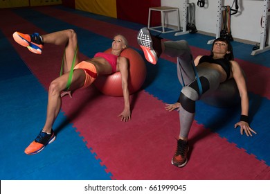 Young Couple Train Together With Resistance Bands On Ball - Leg Exercise In A Health And Fitness Concept - Powered by Shutterstock