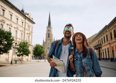 Young couple of travelers laughing and having fun while walking in the city. Copy space. - Powered by Shutterstock