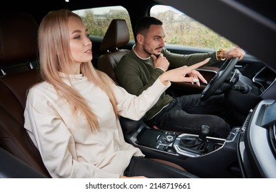 Young couple traveling by car. Man driving comfortable car and thinking about the most profitable route, pretty blonde passenger pointing to road ahead. - Powered by Shutterstock