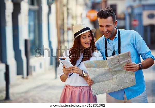 Young couple\
traveling, reading map in the\
city
