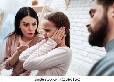 Young couple tries to reach out to small daughter at session with family psychologist. Family of three visit to psychologist.