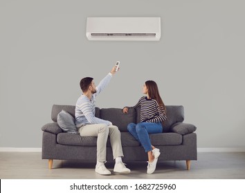 The young couple turns on the air conditioner cools the air while sitting on the sofa in the room
