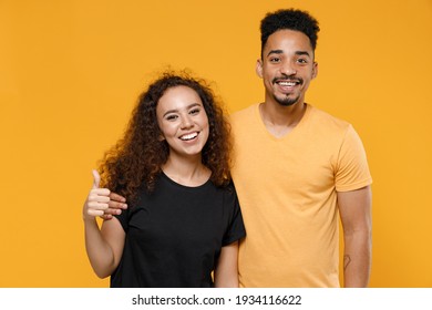 Young Couple Two American Friends Family Happy Satisfied Smiling African Man Woman 20s Together In Black T-shirt Hug Girlfriend Show Thumb Up Like Gesture Isolated On Yellow Background Studio Portrait