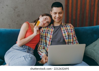 Young Couple Two Friend Man Woman Wear Casual Clothes Using Mobile Cell Phone Credit Bank Card Shopping Online Book Tour Sit On Sofa Together Stay Home Flat Rest Spend Spare Time In Living Room Indoor