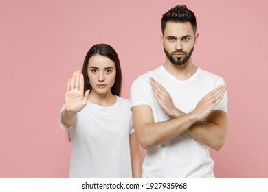 Young couple two friends bearded man woman in white basic blank print design t-shirts say no holding palm folded crossed hands in stop gesture isolated on pastel pink color background studio portrait - Powered by Shutterstock