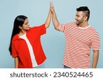Young couple two friends family Indian man woman wear red casual clothes t-shirts together meeting together greeting giving high five clapping hands folded isolated on plain blue cyan color background