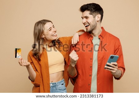 Young couple two friends family man woman wear casual clothes using mobile cell phone credit bank card shopping online order delivery booking tour hugging together isolated on plain beige background