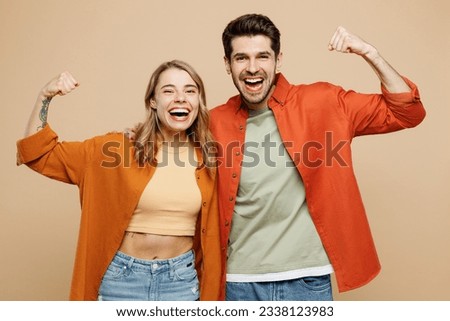 Young couple two friends family man woman wear casual clothes showing biceps muscles on hand demonstrating strength power together isolated on pastel plain light beige color background studio portrait