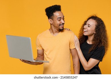 Young Couple Two Friends Together Family African Freelancer Man Woman In Black T-shirt Holding Laptop Pc Computer Working Online Hug Look To Each Other Isolated On Yellow Background Studio Portrait