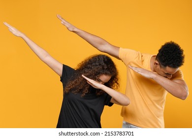 Young Couple Two Friends Together Family African Man Woman 20s In Black T-shirt Doing Dab Hip Hop Dance Hands Move Gesture Youth Sign Hiding Cover Face Isolated On Yellow Background Studio Portrait