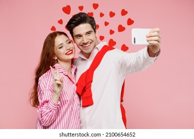 Young couple two friends woman man in casual shirt doing selfie shot on mobile cell phone show v-sign isolated on plain pastel pink background studio. Valentine's Day birthday holiday party concept