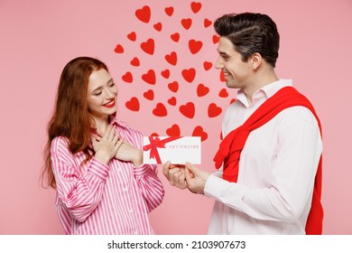 Young couple two friends woman man wear casual shirt hold giving gift certificate coupon voucher card for store isolated on plain pastel pink background. Valentine's Day birthday holiday party concept