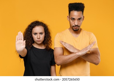 Young Couple Two Strict Serious Friends Family African Man Woman Together In Black T-shirt Do Stop Gesture With Crossed Hands Show Palm Refusing Say No Isolated On Yellow Background Studio Portrait